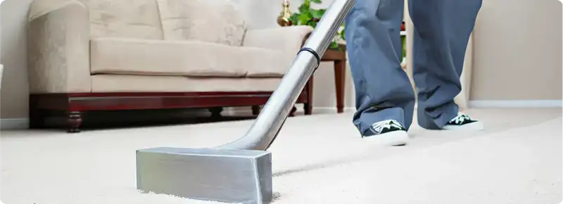 Carpet cleaning technician using a hot-water extraction wand on a light-colored carpet in a living room, Dayton, OH.