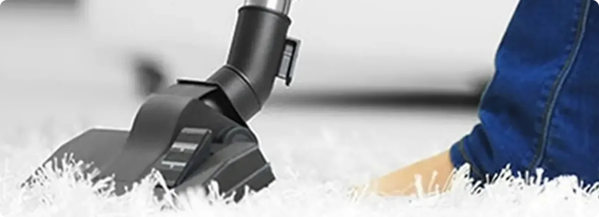 Close-up of a professional vacuuming a white carpet in New Lebanon.