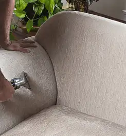 Professional upholstery cleaner deep-cleaning a fabric sofa with a handheld extraction tool and hose Dayton, OH.